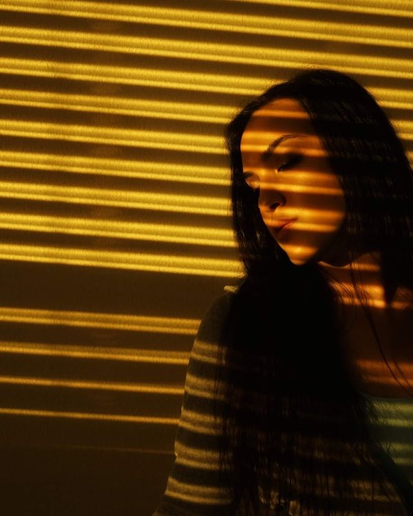 Woman in a calm, focused pose in a dark room with azure light.